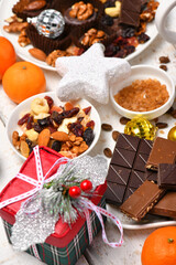 sweet food top view background for merry christmas or new year holiday decoration - chocolate candies, tangerines, cookies, marshmallow and cocoa latte on white wood