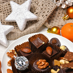 sweet food top view background for merry christmas or new year holiday decoration - chocolate candies, tangerines, cookies, marshmallow and cocoa latte on white wood