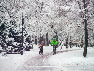 A male father and his little son spend their weekend on bicycles in winter