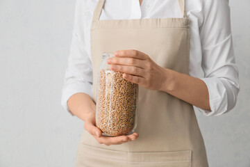 Woman holding jar with wheat grains, closeup