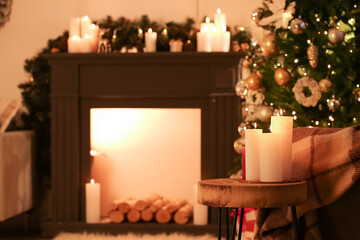 Burning candles in interior of living room decorated for Christmas