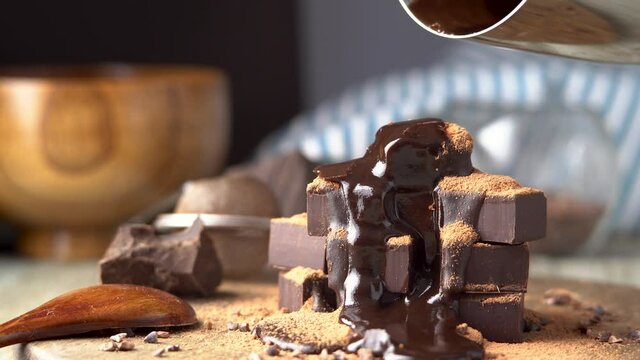 Heap of delicious cubes of bitter dark chocolate sprinkled with cocoa powder and poured with liquid chocolate