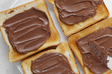 Close-up of bread toast with with chocolate-nut paste spread in white plate