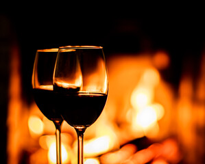 Two glasses of red wine on the background of fireplace lights