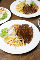 a plate of lamb chop set come with french fries and coleslaw