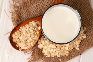 Glass of milk and oat flakes on wooden table