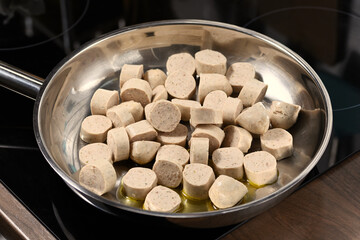 Sliced ​​German sausages in the pan, preparation for frying.