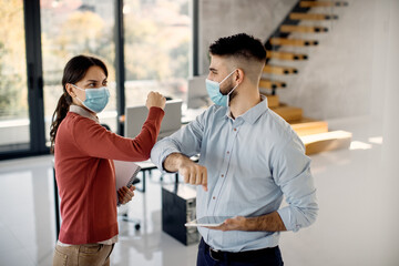 Fototapeta premium Two coworkers greeting with elbows in the office due to COVID-19 pandemic.