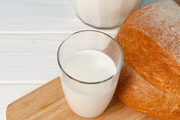 Cup of milk and bread loaf on wooden table