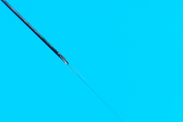 Macro photo of a medical needle from a syringe on a blue background. The concept of vaccination in health care
