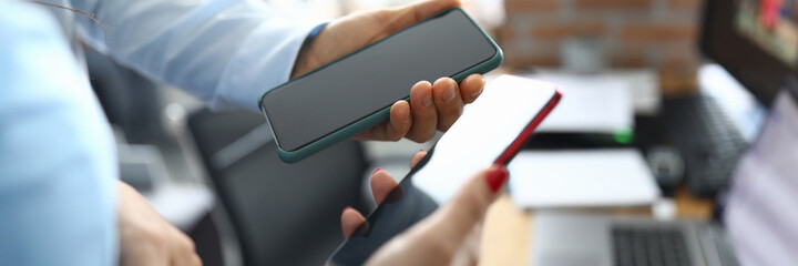 They hold two smartphones in their hands above desktop. Business smartphone app concept