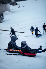 Naklejka premium children having fun riding on tube in winter slide