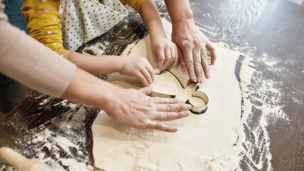 Cookie form used by girl and woman on dough