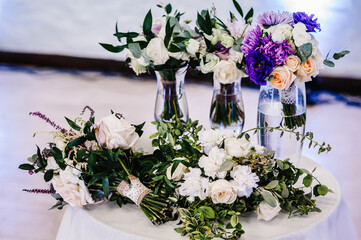 Fototapeta na wymiar Composition of white, violet flowers and greenery on table. Close up. Wedding decor.