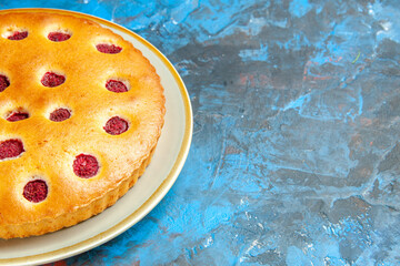 front half view raspberry cake on oval plate on blue table with copy space