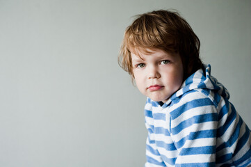 Portrait of a disgruntled child on a gray background.