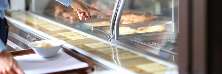 Woman in cafe points to dinner dish on salad tray. Self service in bistro and cafe concept