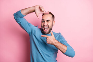 Photo of funky young guy wear blue pullover winking showing camera sign isolated pink color...