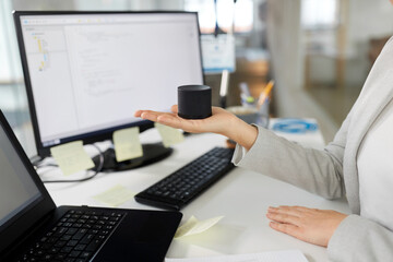 business, technology and internet of things concept - close up of businesswoman using smart speaker at office