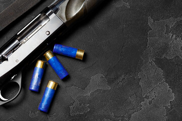 Close up of hunting shotgun and cartridges on dark grey background