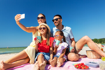 family, leisure and people concept - father, mother and two little daughters taking selfie with smartphone on summer beach