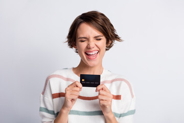 Photo of charming sweet young lady wear striped sweater laughing holding bank card isolated grey color background