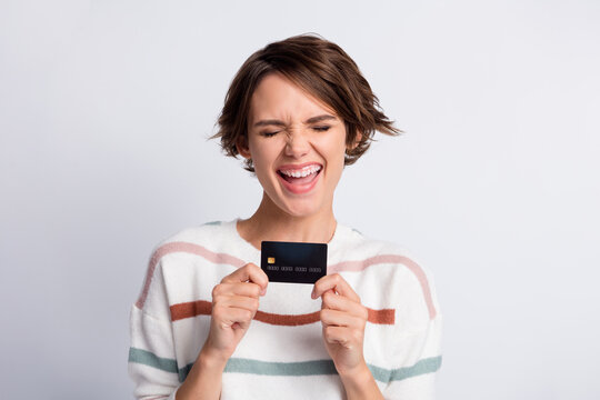Photo of charming sweet young lady wear striped sweater laughing holding bank card isolated grey color background