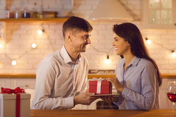 Smiling couple in love giving holiday presents to each other during Valentines day celebration