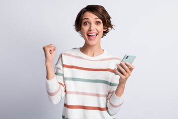 Fototapeta premium Photo of excited young lady wear striped sweater holding modern gadget rising fist isolated grey color background