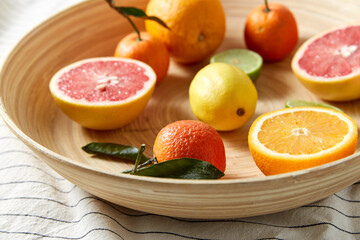 food, healthy eating and vegetarian concept - close up of citrus fruits on wooden plate