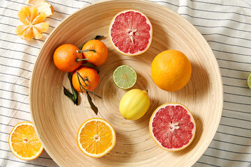 food, healthy eating and vegetarian concept - close up of citrus fruits on wooden plate