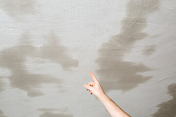 Young adult man finger pointing to wet and dry putty ceiling. Drying process. Closeup. Repair work...