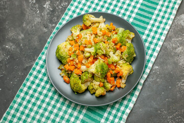 Overhead view of healthy vegetable salad on green stripped towel on gray background