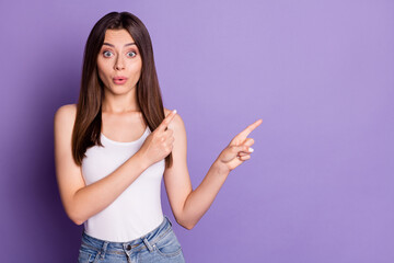 Photo of funny impressed young woman wear casual white outfit pointing two fingers empty space lips pouted isolated violet color background