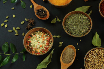 Wide variety spices and herbs on background of black table