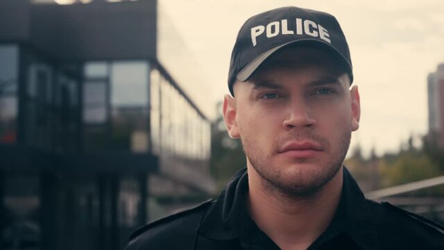 Policeman in cap walking while patrolling urban street