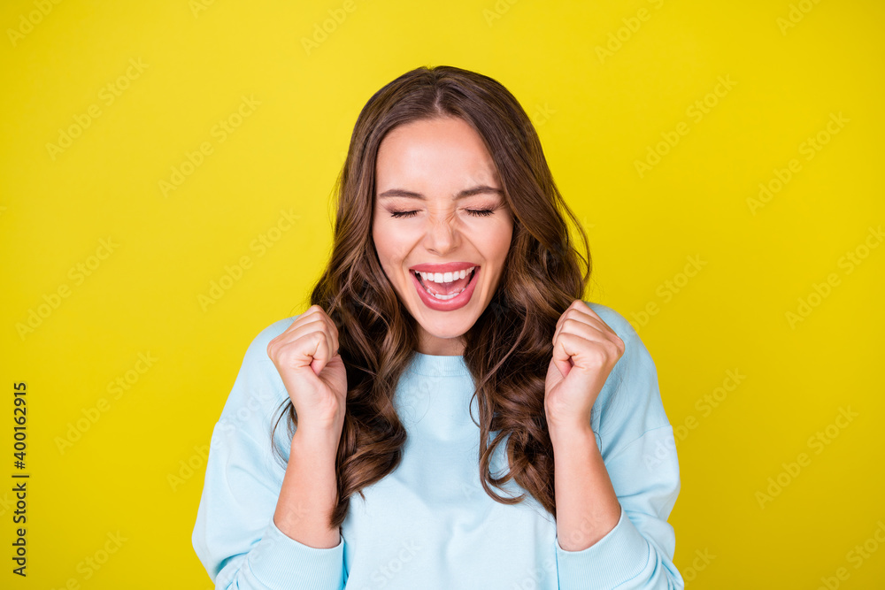 Wall mural Photo of cute funny young girl raise fists open mouth eyes closed delighted screaming yeah win big bet horse racing wear blue pullover isolated vibrant yellow color background