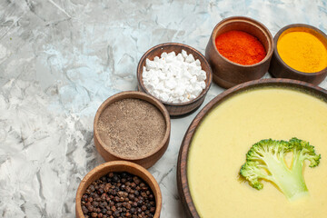 Creamy broccoli soup in a brown bowl and different spices on gray background stock image