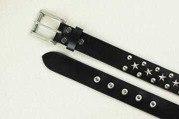 black leather belt close-up with silver stars and holnitens on a blurred gray background top view