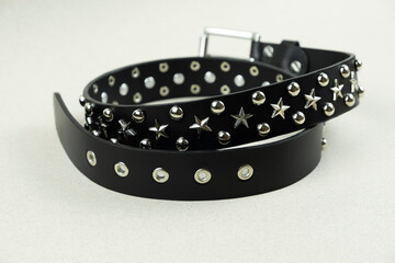 black leather belt with silver stars and caps on blurred gray background