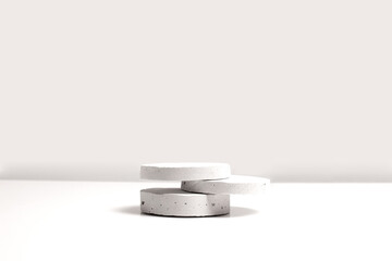 Gray cocncrete circle shaped pedestals on white table with copy space, side view. Podium mockup background for products. Advertising template. Stone platform. Abstract geometric pedestal.