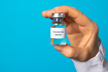 A doctor or laboratory technician holds a test tube with a vaccine against diseases. Vaccination against covid-19 coronavirus. Pandemic in the world, the invention of the vaccine. Banner text place.