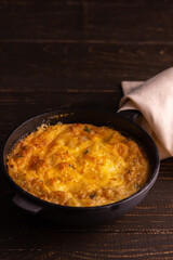 Frittata with cheese, mozzarella and stewed pumpkin in a cast iron pan on a wooden background