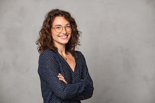 Successful smiling woman wearing eyeglasses on grey wall