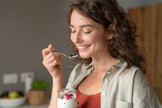 Woman eating yogurt with berries at home