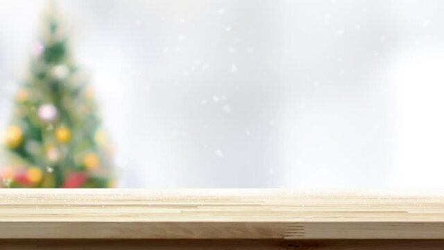 Beautiful wood table top with snow and blurred Christmas tree in background for product display 