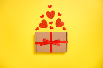 Valentine day greeting card composition. Gift box craft paper with hearts on yellow background. Top view,flat lay, copy space