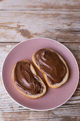 Spread the chocolate-nut cream on slices of bread. Delicious Breakfast with chocolate and nut paste. Copy space.