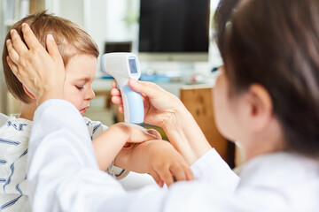 Kinderarzt beim Fieber messen mit Stirnthermometer