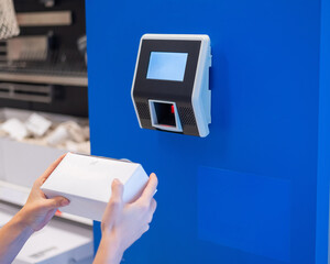 A faceless woman uses a price scanner on the wall